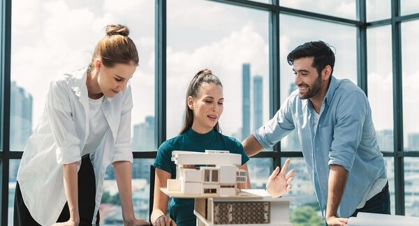 melhores empresas de arquitetura residencial - Uma equipa de arquitetos trabalha em conjunto na construção de uma maqueta de uma casa