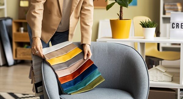melhores empresas de decoração de interiores - Um designer de interiores compara cores com um móvel para escolher a melhor decoração para a sala de estar de uma casa.