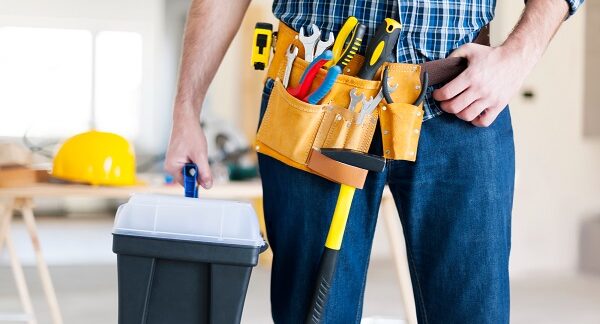 melhores empresas de manutenção residencial - Um trabalhador usa um cinto de ferramentas e transporta também uma caixa de ferramentas.